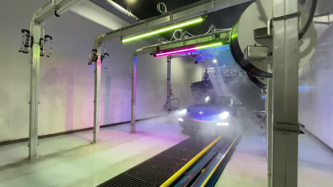 Inside a Century Express wash tunnel, arch lighting raking across a car mid-wash