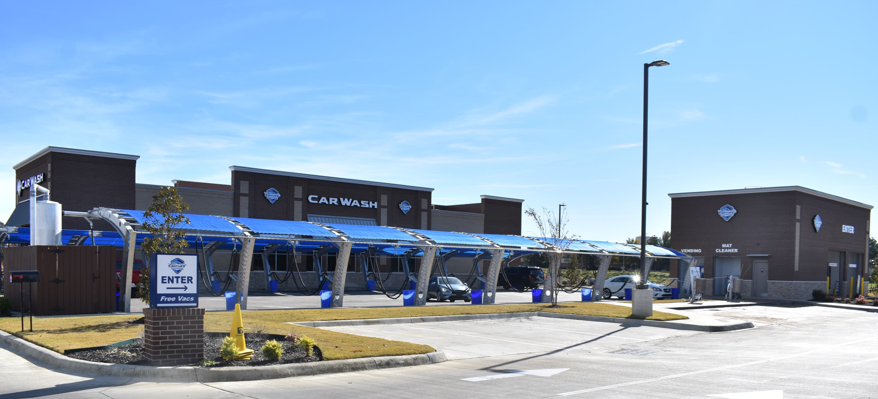 A Century Express Carwash location exterior, showing the covered wash tunnel, entrance and free vacuum stalls.