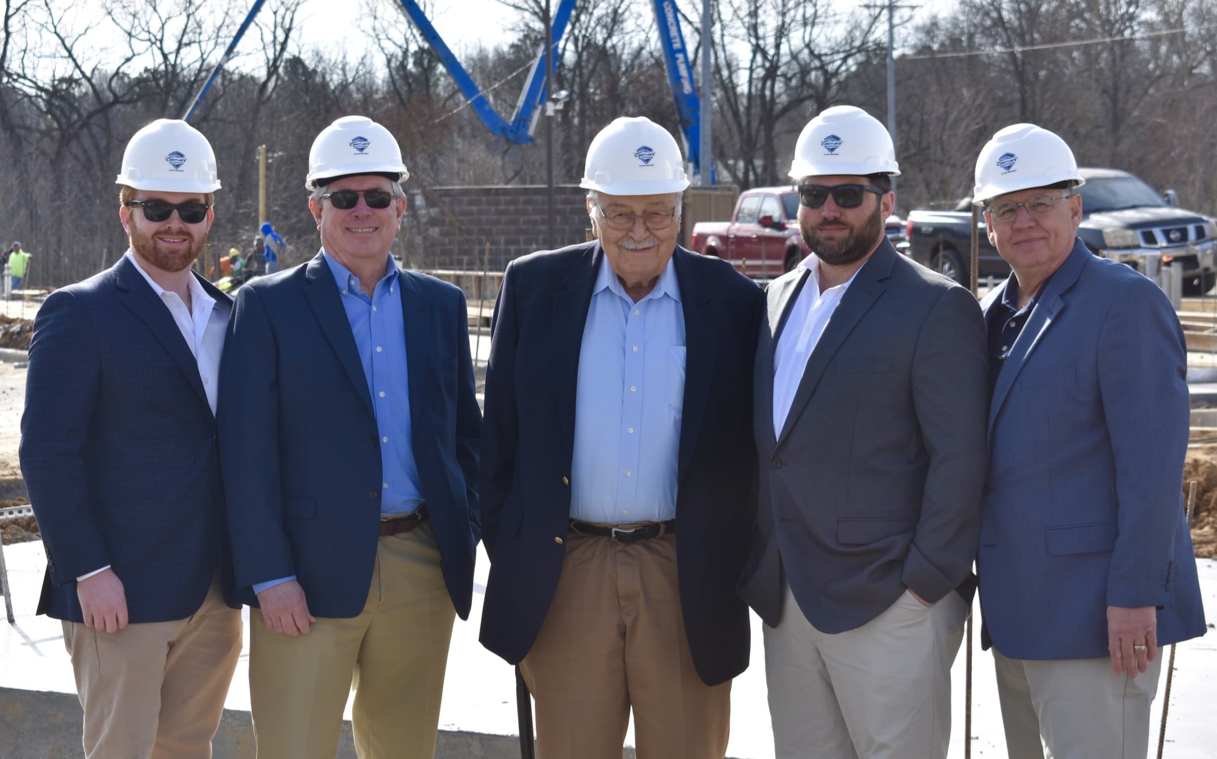 Five people in hard hats branded with the Century Car Wash logo at a groundbreaking ceremony for a new location.
